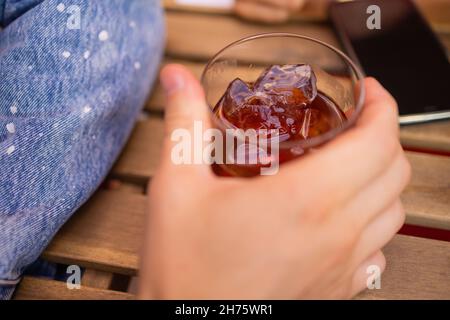 Ein rot-saurer Cocktail in einem Coupé-Glas, dekoriert mit einem Tannenzweig auf dem Tisch in einer Bar Stockfoto