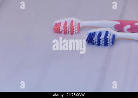 Zwei Zahnbürsten aus der Nähe - eine blaue und eine rosa mit einer grauen Oberfläche mit Kopierfläche Stockfoto