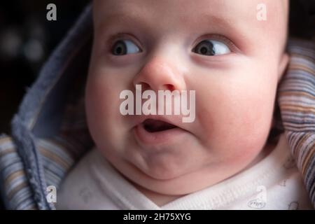 Drei Monate Baby schaut beiseite mit finny überrascht Ausdruck. Stockfoto