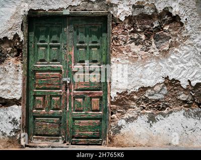 Alte, alte, grüne Tür an einer alten stonierten Wand. Stockfoto