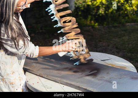 Foto mit Kopierraum einer Frau, die im Freien Polystyrol-Buchstaben malt Stockfoto