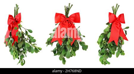 Drei Bündchen frischer grüner Misteln, gebunden mit leuchtend roten Weihnachtsbögen. Isoliert auf Weiß. Stockfoto