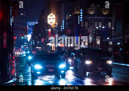 Toronto, Kanada - 10 30 2021: Nächtlicher Regen auf Autos, die an der Ampel in der Yonge Street in der Innenstadt von Toronto stehen, mit einer hellen, farbenfrohen Straße Stockfoto
