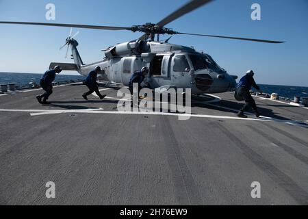 211119-N-TC847-1481 OSTCHINESISCHES MEER (NOV 19, 2021) Seeleute entfernen Choke und Ketten zu einem MH-60s Seahawk, der dem Hubschrauber-Seekampfgeschwader (HSC 4) zugewiesen ist. Higgins wird Commander, Task Force (CTF) 71/Destroyer Squadron (DESRON) 15, der größten vorwärtseingesetzten DESRON der Marine und der wichtigsten Surface Force der US-Flotte von 7th, zugewiesen. (USA Navy Foto von Mass Communication Specialist 3rd Class Christine Montgomery/veröffentlicht) Stockfoto