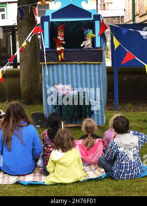 Genießen Sie eine traditionelle Punch und Judy Show. Frau schlägt auf eine Kirche Fete!Handpuppe-Show mit verkleideten Stimmen Stockfoto