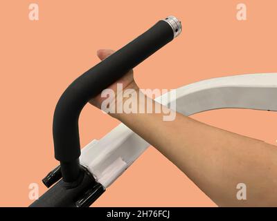 Behinderte Person mit Bicep Curl Machine. Auf peachy Pastell Hintergrund. Stockfoto