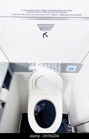 Schmale Toilettenkabine und Sitz im Badezimmer der Fluggesellschaft Boeing 737-800. Öffentliche Einrichtungen und Toiletten an Bord des Flugzeugs. Stockfoto