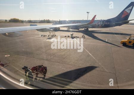 Blick auf einen Boeing 737-800-Flügel und einen Flugplatz durch das Flugzeugkabinenfenster am Mittag Stockfoto