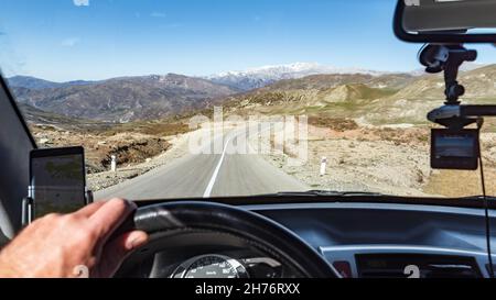 Blick auf die Straße in den Bergen durch die Windschutzscheibe des Autos Stockfoto