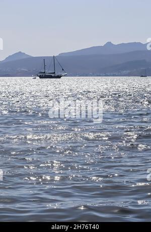 Blaue Meereswellen funkeln in der Sonne und eine Yacht. Sommerferien Konzept Stockfoto