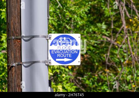 Flutverdampfungsweg-Schild mit einem Pfeil nach rechts auf dem Straßenpfahl. Verschwommener grüner Hintergrund. Stockfoto