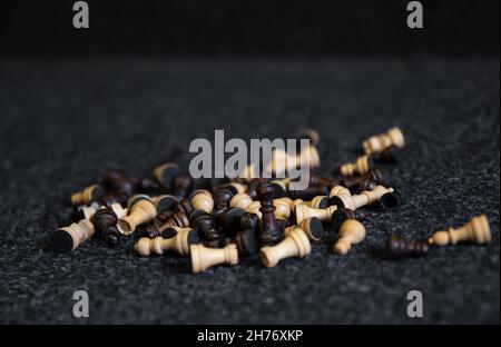 Verstreute Schachfiguren auf einem verschwommenen schwarzen Hintergrund. Stockfoto