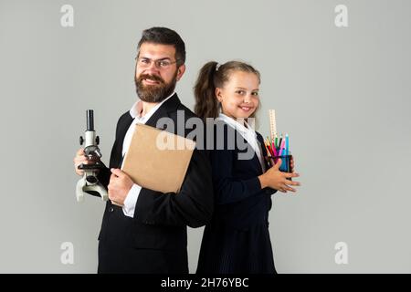 Lächelnde Lehrerin mit aufgeregt glücklich Schüler Schulmädchen. Porträt von lustigen Schulmädchen und Tutor mit Schulbedarf. Glückliche Lehrerin und Schülerin Mädchen auf Stockfoto