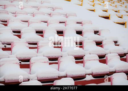 Plastiksitze in einer Reihe am Stadion sind mit Schnee bedeckt. Stockfoto