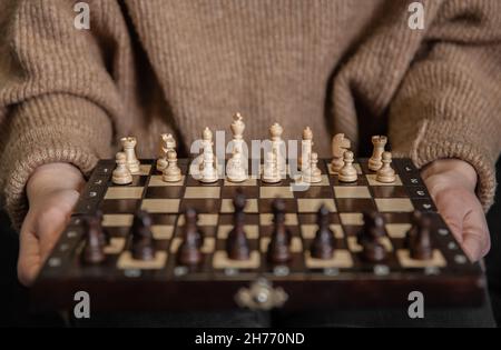 Schachbrett mit hölzernen Schachfiguren in weiblichen Händen. Stockfoto