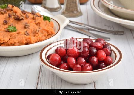 Schüssel mit frischen Preiselbeeren auf einem Feiertagsesstisch mit Kartoffelpüree Stockfoto