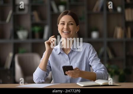 Porträt einer glücklichen erfolgreichen Geschäftsfrau sitzen mit dem Smartphone am Schreibtisch Stockfoto