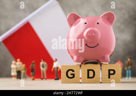 Sparschwein, Holzwürfel mit Text und Spielzeug Männer aus Kunststoff auf dem Hintergrund der Flagge, das Konzept zum Thema Polen BIP Stockfoto