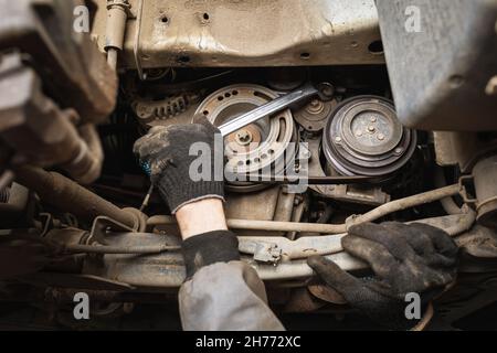 Ein Automechaniker entfernt die alte Wasserpumpe eines Automotors Stockfoto