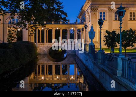 Abend im Royal Lazienki Park in Warschau, Polen. Neoklassizistische Kanalbrücke mit Kolonnade und Spiegelung im Wasser, Teil des Palastes auf der Isle Fro Stockfoto