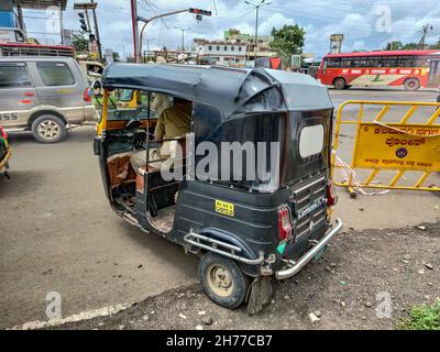 GULBARGA, INDIEN - 04. Okt 2021: Eine schwarze Auto-Rikscha parkte am Straßenrand an einem hellen sonnigen Nachmittag und wartete auf Passagiere in Indien Stockfoto