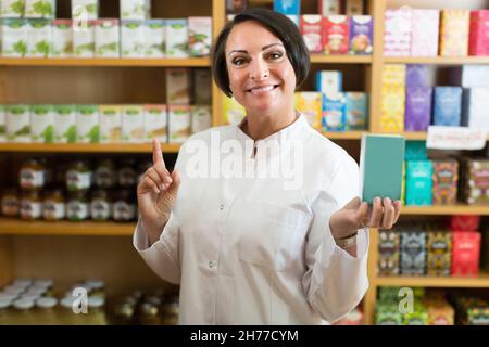 Lächelnde reife Frau Verkäufer hält Nährstoffe Stockfoto