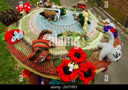 Eine Häkelauflage auf einer Royal Mail-Säulenbox mit Blumen und Tieren. Bürgersteig in Basingstoke, Hampshire. Stockfoto