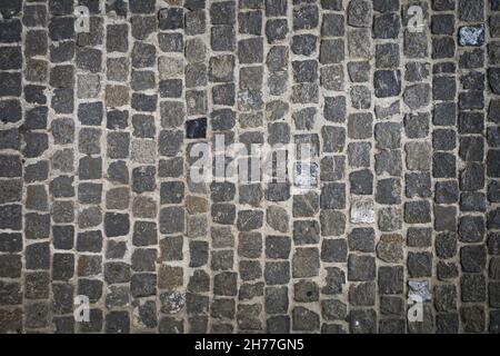 Aufnahme eines Kopfsteinpflasters auf dem Boden einer städtischen Straße in Grau- und Strukturtönen. Hintergrundkonzept. Stockfoto