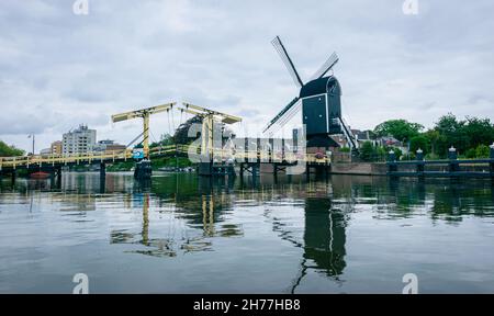 Typisch holländischer Blick auf eine Windmühle und eine Zugbrücke über einen Kanal. Windmühle 'De Put' und Zugbrücke 'Rembrandtbrug' in der historischen Stadt Leiden, Holland. Stockfoto