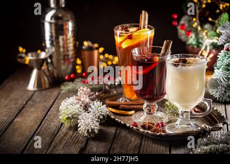 Frischer gelber Eierwein, Grog und fruchtiger roter Glühwein mit weihnachtlicher Dekoration. Auswahl an alkoholischen Heißgetränken im Herbst oder Winter Stockfoto