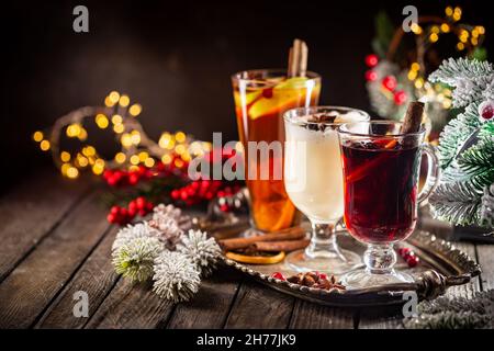 Frischer gelber Eierwein, Grog und fruchtiger roter Glühwein mit weihnachtlicher Dekoration. Auswahl an alkoholischen Heißgetränken im Herbst oder Winter Stockfoto