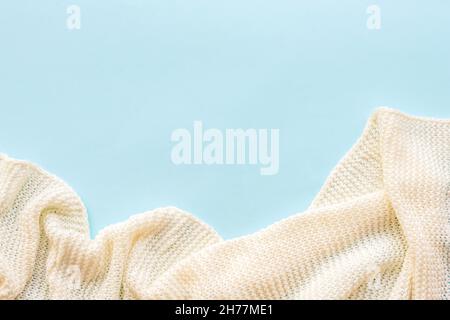 Weiße Strickdecke auf blauem Hintergrund. Draufsicht, flach liegend, Kopierbereich. Stockfoto