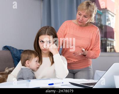 Erwachsene Frauen mit ihrer Mutter haben Unstimmigkeiten wegen Problemen beim Ausfüllen von Dokumenten Stockfoto