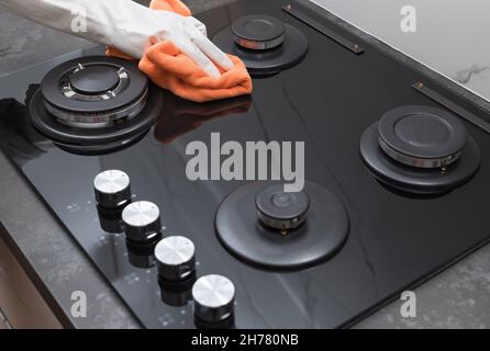 Gasherd wird gereinigt. Person Hand Polieren Glas mit Mikrofaser Stockfoto