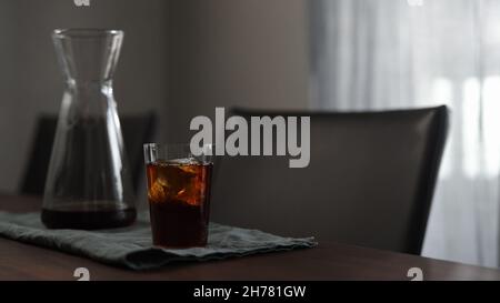 Frischer Kaffee mit Eisfelsen im Glas auf Holztisch, breites Foto Stockfoto