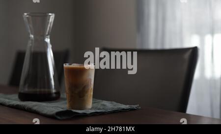 Frischer Kaffee mit Milch im Glas auf Holztisch, breites Foto Stockfoto