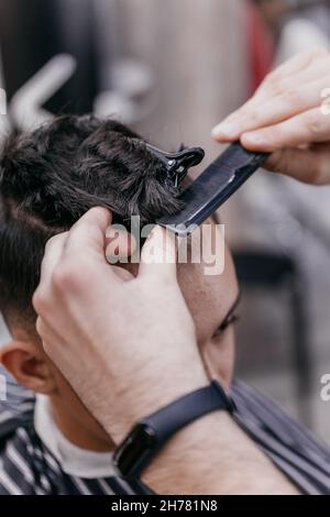 Friseurhands schneiden die Haare mit einer Schere aus nächster Nähe. Stockfoto