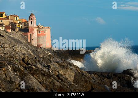 Tellaro Dorf mit der Kirche des heiligen Georg (San Giorgio), mit Klippen und weißen Meereswellen. La Spezia, Ligurien, Italien Stockfoto