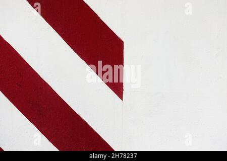 Abstrakt geometrische Wand Textur Hintergrund. Alte weiße Stuckzementwand mit diagonalen roten Streifen bemalt Stockfoto