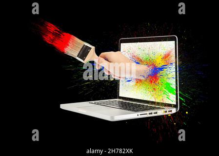 Eine Hand mit einem Pinsel ragt aus dem Laptop-Bildschirm. Isoliert auf Schwarz. Spritzwasser von mehrfarbigem Lack in verschiedene Richtungen. Konzept Stockfoto