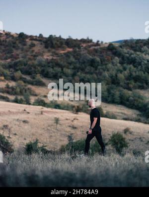 Ein glatzköpfiger Mann in Schwarz, der auf einem Feld läuft Stockfoto