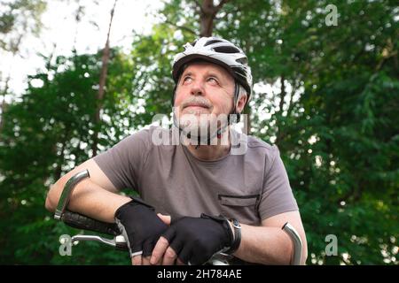 Älterer Mann auf dem Fahrrad während der schönen Sommerzeit im Wald, lächelnd, genießen Reise Stockfoto