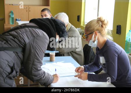 Sofia, Bulgarien. 21st. November 2021. Eine Frau meldet sich für die zweite Runde der Präsidentschaftswahlen in einem Wahllokal in Sofia, Bulgarien, am 21. November 2021 an. Die Bulgaren gingen am Sonntagmorgen zur Wahl, um in der zweiten Runde der Präsidentschaftswahlen zu stimmen. Fast 6,7 Millionen Wahlberechtigte würden ihren Präsidenten für die nächsten fünf Jahre zwischen dem amtierenden Präsidenten Rumen Radev und dem Rektor der Universität Sofia, Anastas Gerdjikov, wählen. Quelle: Marian Draganov/Xinhua/Alamy Live News Stockfoto