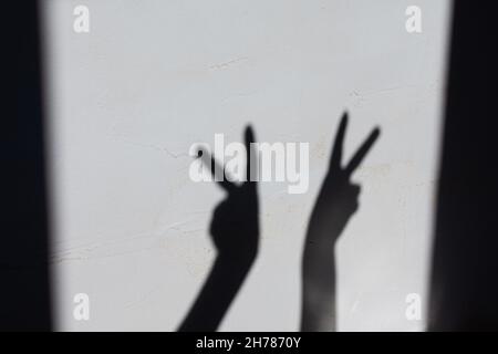 Schatten von weiblichen Händen an einer Betonwand zeigen die Hände das Zeichen von victorie Stockfoto