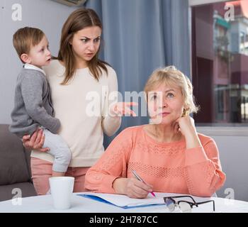 Erwachsene Frauen mit ihrer Mutter haben Unstimmigkeiten wegen Problemen beim Ausfüllen von Dokumenten Stockfoto