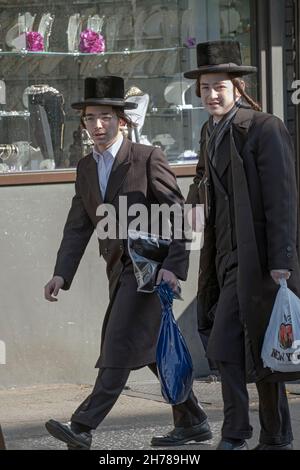 2 orthodoxe jüdische Jungen, die sich sehr ähnlich gekleidet haben, wahrscheinlich Teenager, gehen an einem Freitagnachmittag auf der Lee Avenue spazieren. In Williamsburg, Brooklyn, New York City. Stockfoto