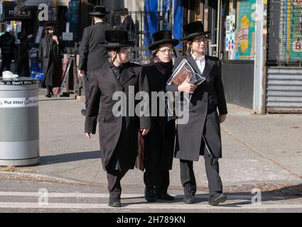 3 orthodoxe jüdische Jungen, wahrscheinlich Teenager, die sich sehr ähnlich kleideten, gehen an einem Freitagnachmittag auf der Lee Avenue spazieren. In Williamsburg, Brooklyn, New York City. Stockfoto