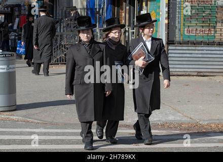 3 orthodoxe jüdische Jungen, wahrscheinlich Teenager, die sich sehr ähnlich kleideten, gehen an einem Freitagnachmittag auf der Lee Avenue spazieren. In Williamsburg, Brooklyn, New York City. Stockfoto