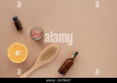 Natürliche Bio-Kosmetikprodukte, Öl, Serumflasche, Pinsel, himalaya-Rosa-Salz im Glas und orangefarbene Hälften auf beigem Hintergrund. Draufsicht, flaches Lay, c Stockfoto