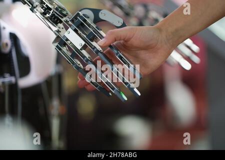 Weibliche Hand, die eine Cyborg-Metallhand hält Stockfoto